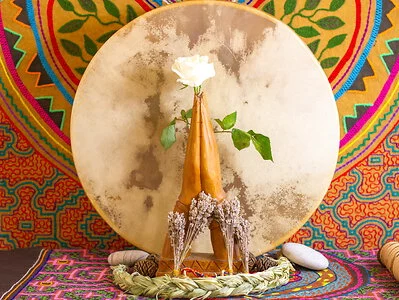 Hands in praying position holding white rose in front of moon and colourful backdrop